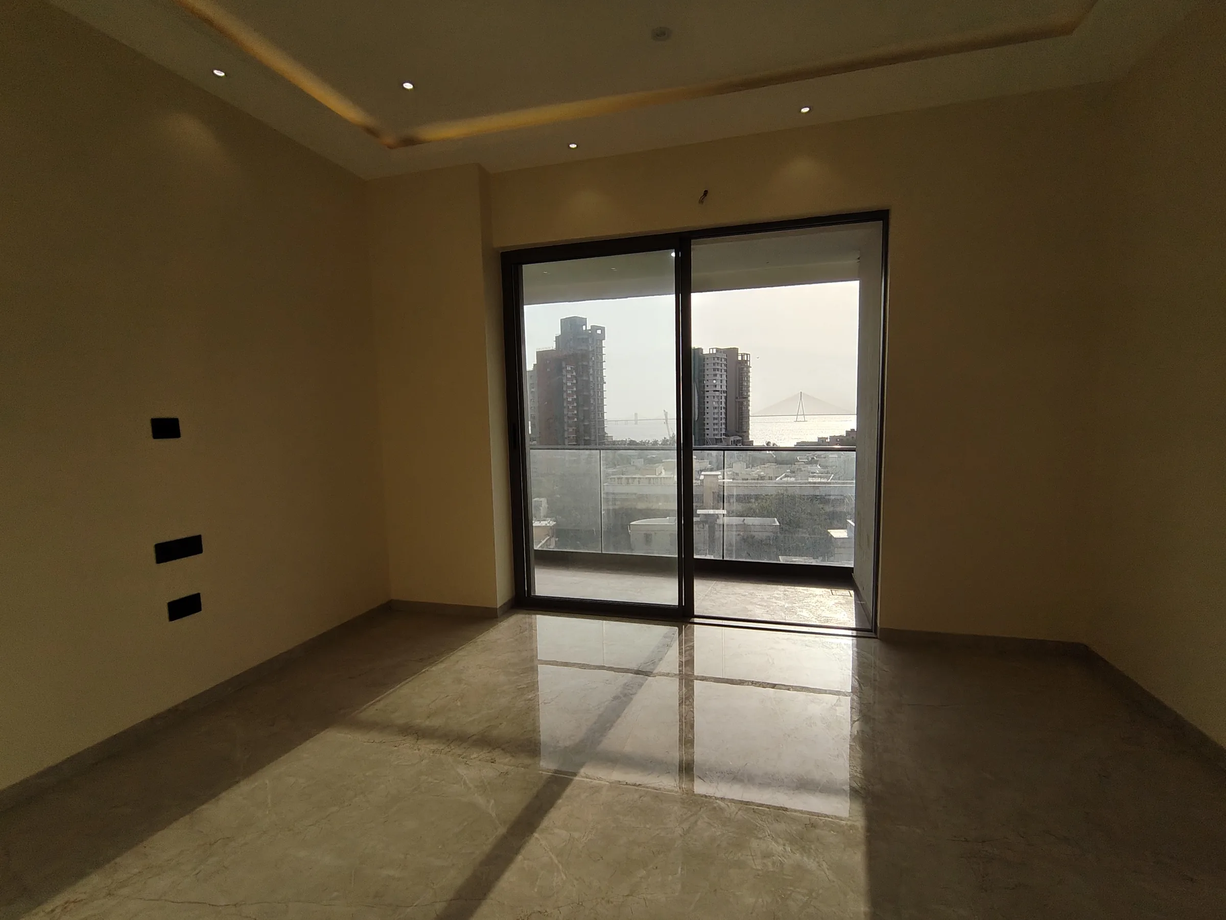 Actual bedroom at Moraj Shivaji Park with a glass door framing the Bandra–Worli Sea Link